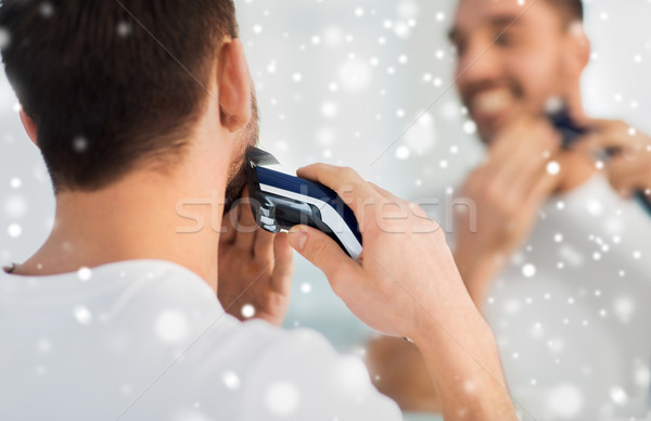 close up of man shaving beard with trimmer Stock photo © dolgachov