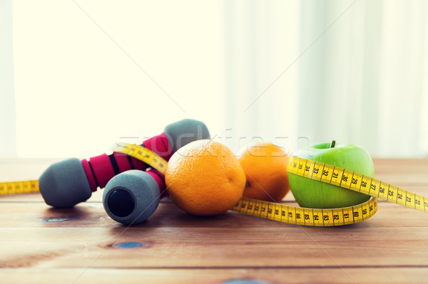 close up of dumbbell, fruits and measuring tape Stock photo © dolgachov