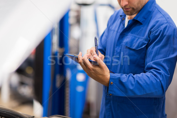 auto mechanic with clipboard at car repair shop Stock photo © dolgachov