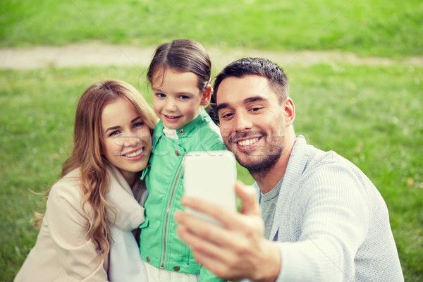 Stock photo: happy family taking selfie by smartphone outdoors