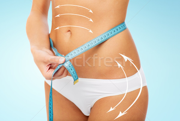 Stock photo: close up of woman body with measure tape on waist
