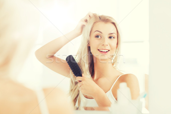 happy woman brushing hair with comb at bathroom Stock photo © dolgachov