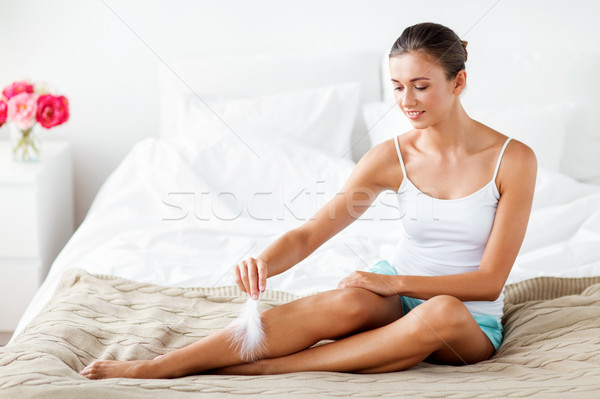 woman with feather touching bare legs on bed Stock photo © dolgachov