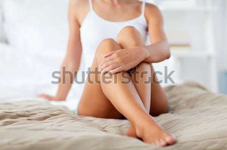 woman with feather touching her hand skin on bed Stock photo © dolgachov