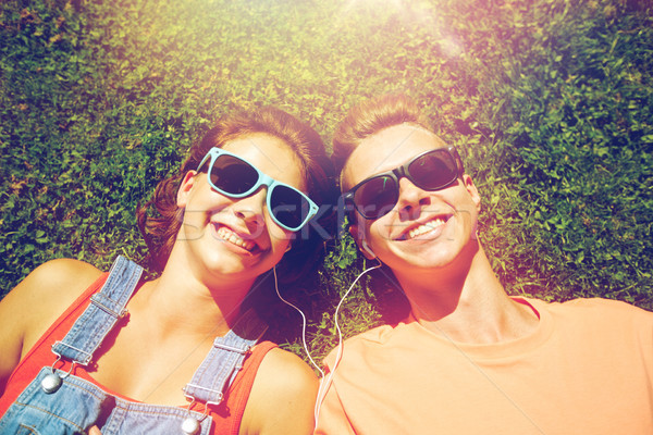 happy teenage couple with earphones lying on grass Stock photo © dolgachov