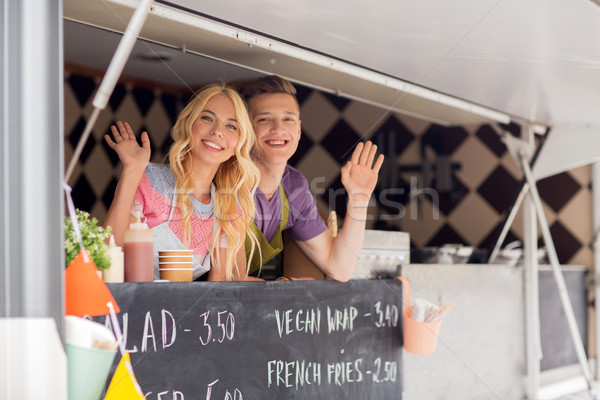 happy young sellers waving hands at food truck Stock photo © dolgachov