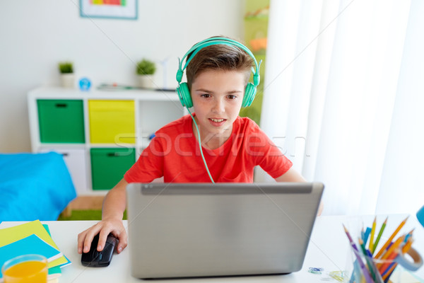 Stock photo: boy in headphones playing video game on laptop