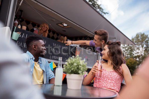 friends with drinks sitting at table at food truck Stock photo © dolgachov