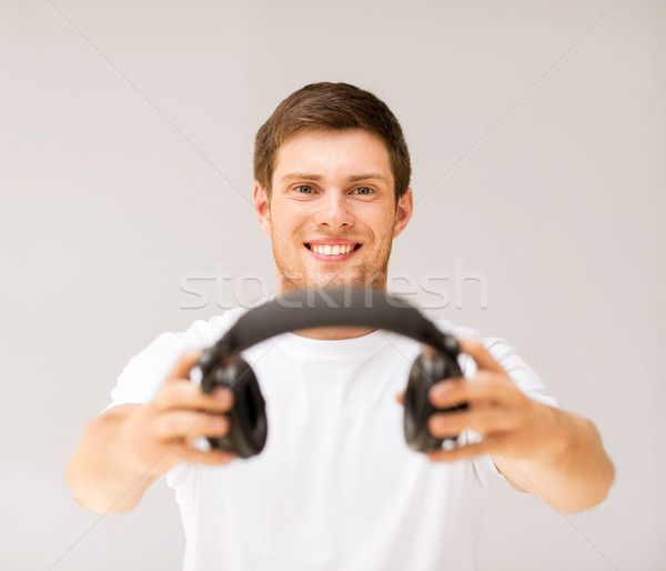 young smiling man offering headphones Stock photo © dolgachov