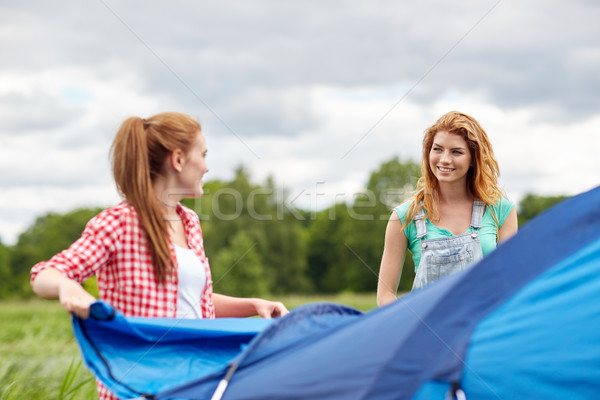 smiling friends setting up tent outdoors Stock photo © dolgachov