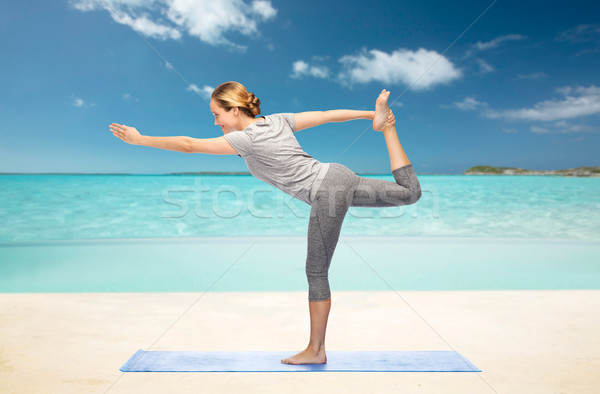 woman making yoga in lord of the dance pose on mat Stock photo © dolgachov