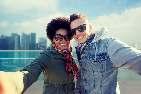 happy teenage couple taking selfie in singapore Stock photo © dolgachov