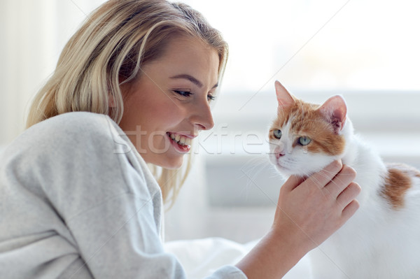 happy young woman with cat in bed at home Stock photo © dolgachov
