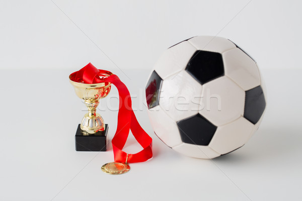close up of football ball, golden cup and medal Stock photo © dolgachov