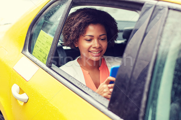 Stock photo: happy african woman texing on smartphone in taxi