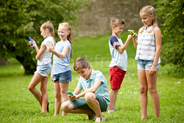 kids with smartphones playing game in summer park Stock photo © dolgachov