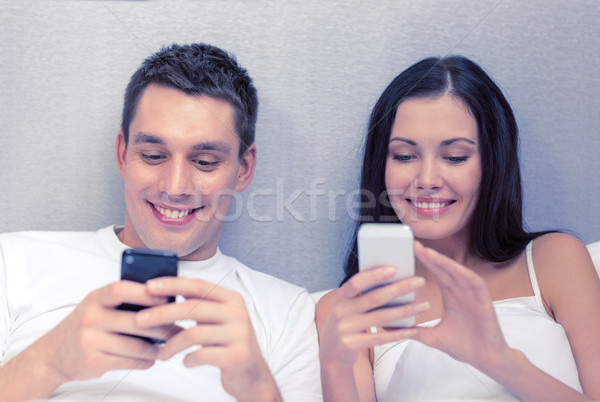 smiling couple in bed with smartphones Stock photo © dolgachov