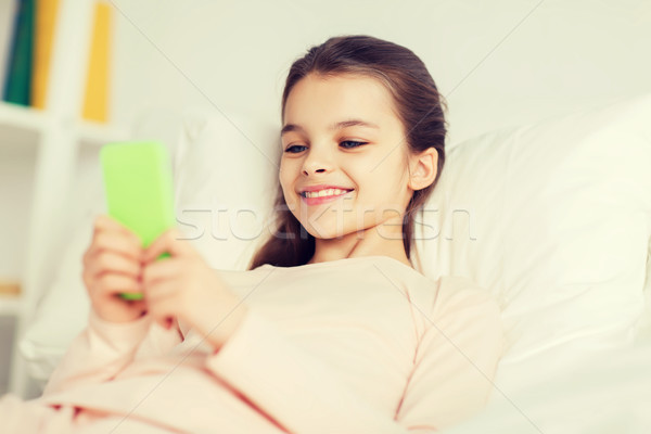 Ragazza felice letto smartphone home persone bambini Foto d'archivio © dolgachov