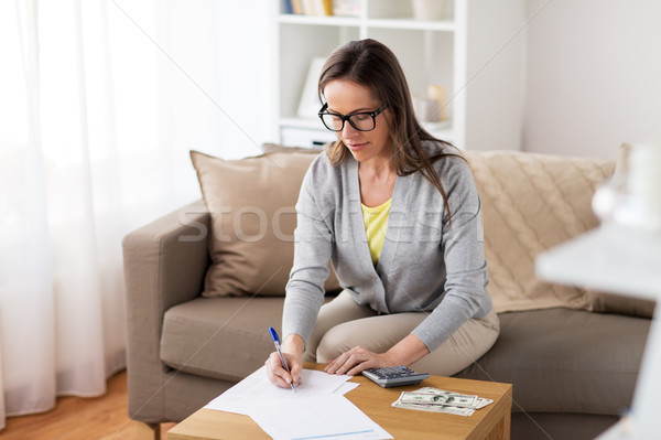 woman with money, papers and calculator at home Stock photo © dolgachov