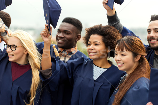 happy graduates or students waving mortar boards Stock photo © dolgachov