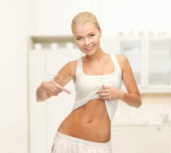 beautiful sporty woman pointing at her abs Stock photo © dolgachov