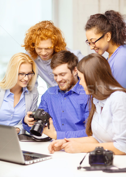 smiling team with laptop and photocamera in office Stock photo © dolgachov