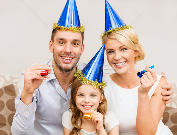 smiling family in blue hats blowing favor horns Stock photo © dolgachov