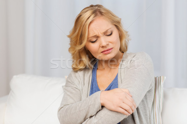 unhappy woman suffering from pain in hand at home Stock photo © dolgachov