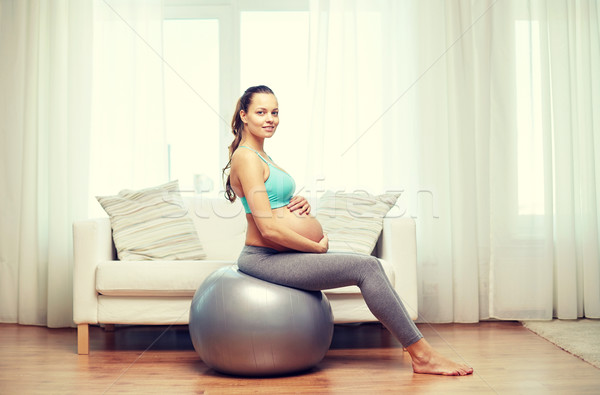 Stock photo: happy pregnant woman exercising on fitball at home