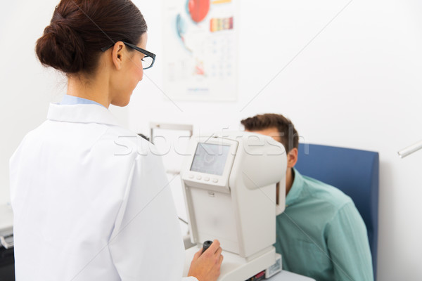 optician with autorefractor and patient at clinic Stock photo © dolgachov