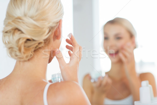 Stock photo: close up of woman applying face cream at bathroom