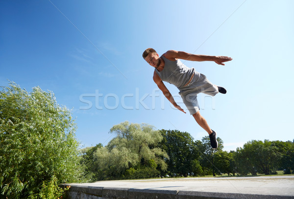 sporty young man jumping in summer park Stock photo © dolgachov