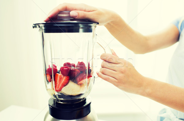 Stock photo: close up of woman with blender making fruit shake