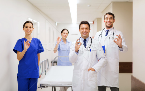 Stock photo: happy doctors with gurney showing ok at hospital