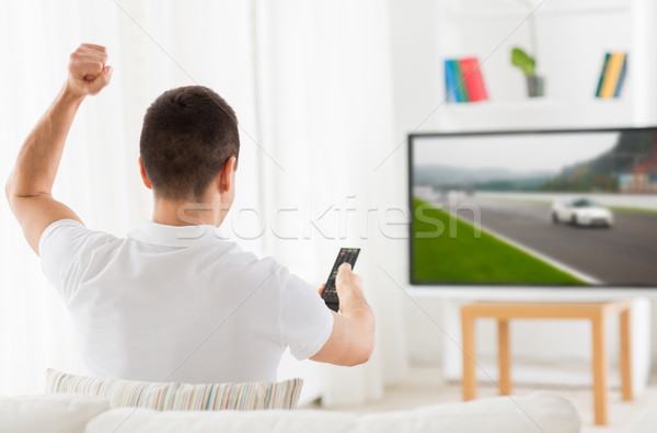 man with remote watching motorsports on tv at home Stock photo © dolgachov