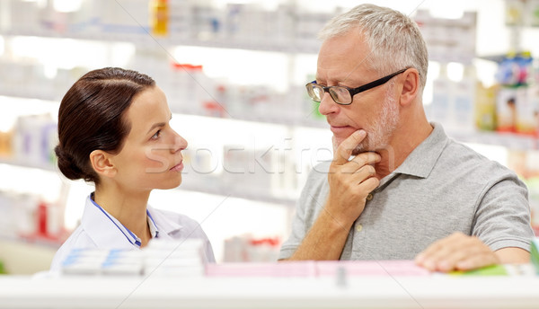 pharmacist showing drug to senior man at pharmacy Stock photo © dolgachov