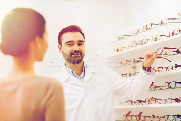 woman and optician showing glasses at optics store Stock photo © dolgachov