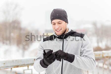 happy man with earphones and smartphone in winter Stock photo © dolgachov