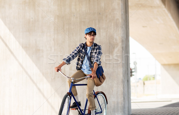 Stock photo: young hipster man with bag riding fixed gear bike