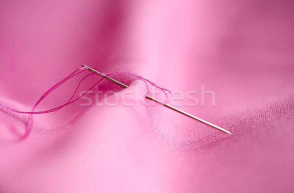 sewing needle with thread stuck into pink fabric Stock photo © dolgachov