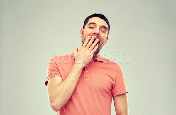 yawning man over gray background Stock photo © dolgachov