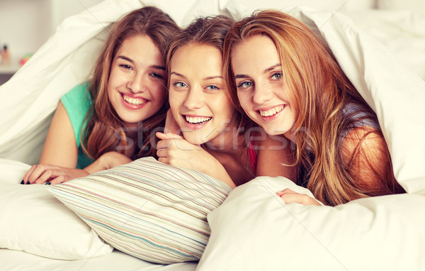 happy young women in bed at home pajama party Stock photo © dolgachov
