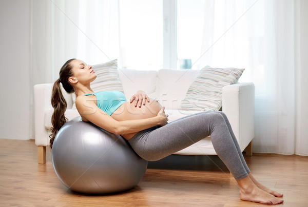 Stock photo: happy pregnant woman exercising on fitball at home