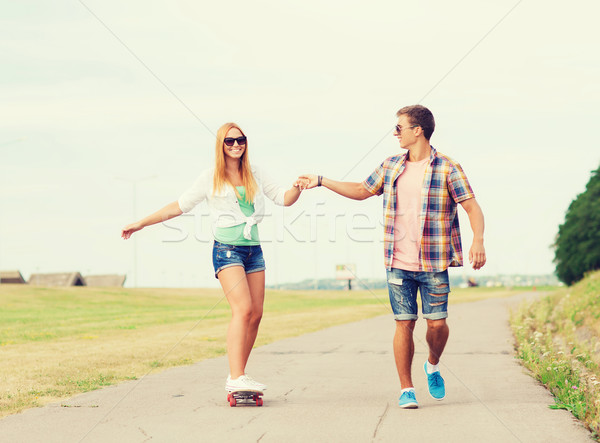 smiling couple with skateboard outdoors Stock photo © dolgachov