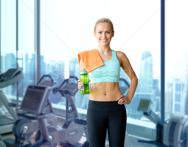 happy woman with bottle of water and towel in gym Stock photo © dolgachov