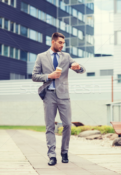 young serious businessman with paper cup outdoors Stock photo © dolgachov