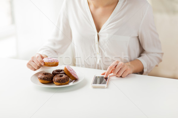 close up of hands with smart phone and donuts Stock photo © dolgachov