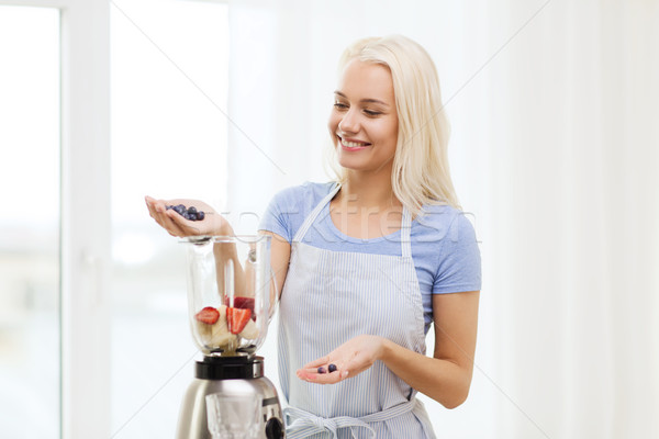 Stock photo: smiling woman with blender preparing shake at home