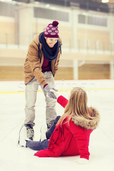 man helping women to rise up on skating rink Stock photo © dolgachov