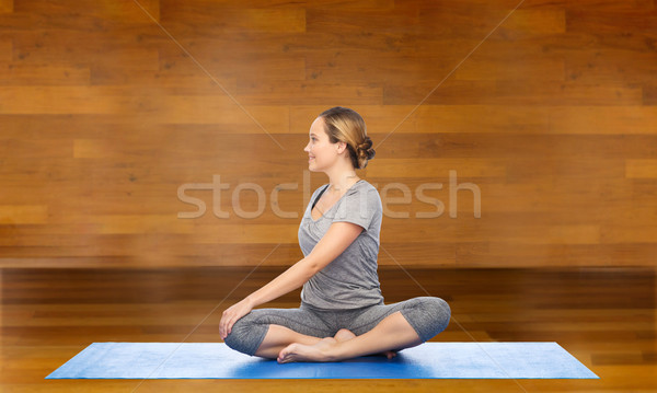 woman making yoga in twist pose on mat Stock photo © dolgachov